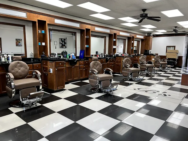 Inside Next Gen Barbershop: a row of walnut barber stations and tan leather chairs on a black and white checkerboard floor