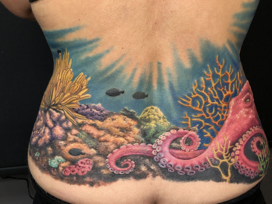 Lower back tattoo of a coral reef with a pink octopus, fish and sun rays