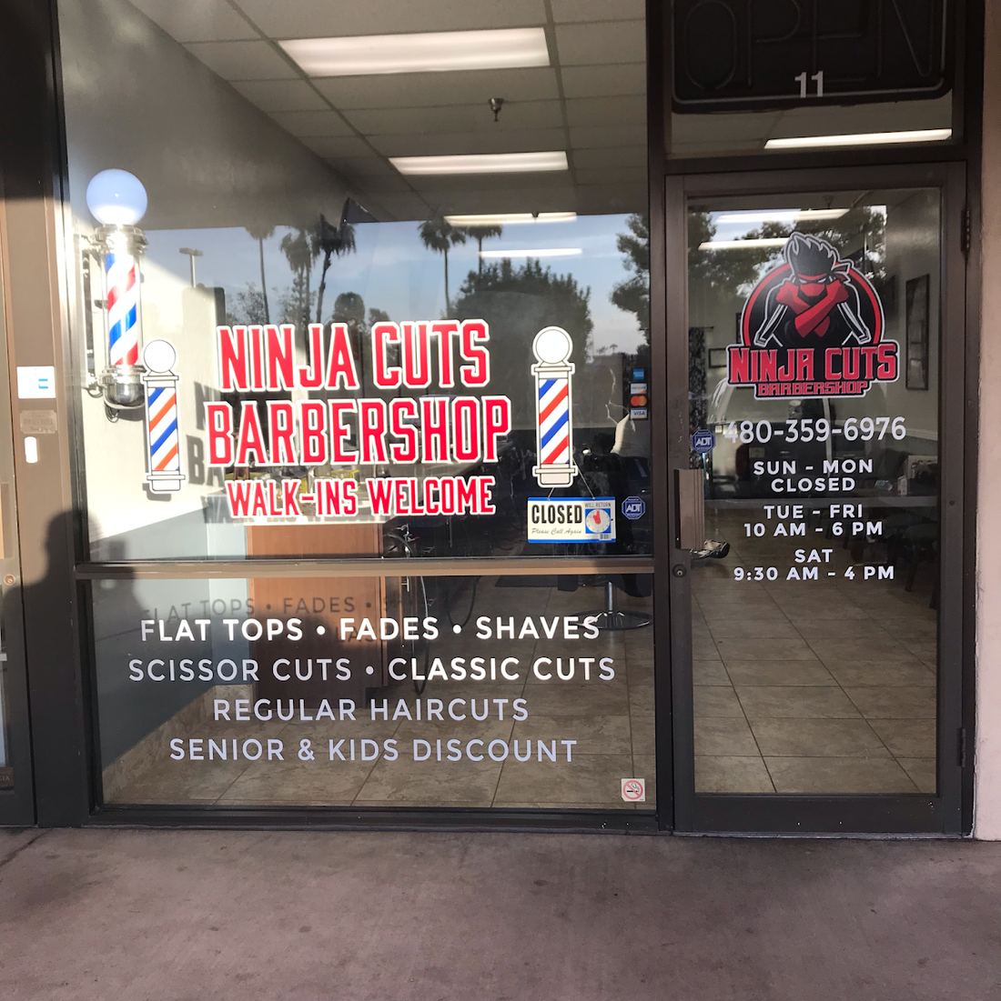 Ninja Cuts Barbershop storefront window with the red logo and barber poles