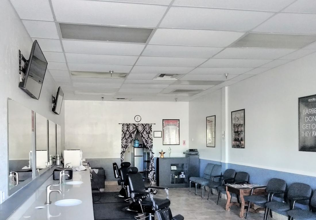 Inside Ninja Cuts: a long row of barber stations, mirrors and wall screens with waiting chairs at the back