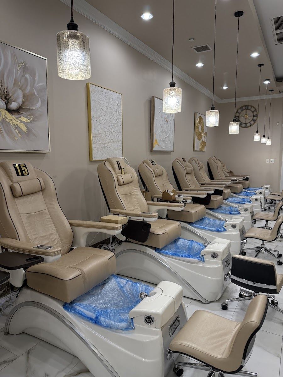 Pedicure stations lined along the salon with soft gray chairs and pendant lights