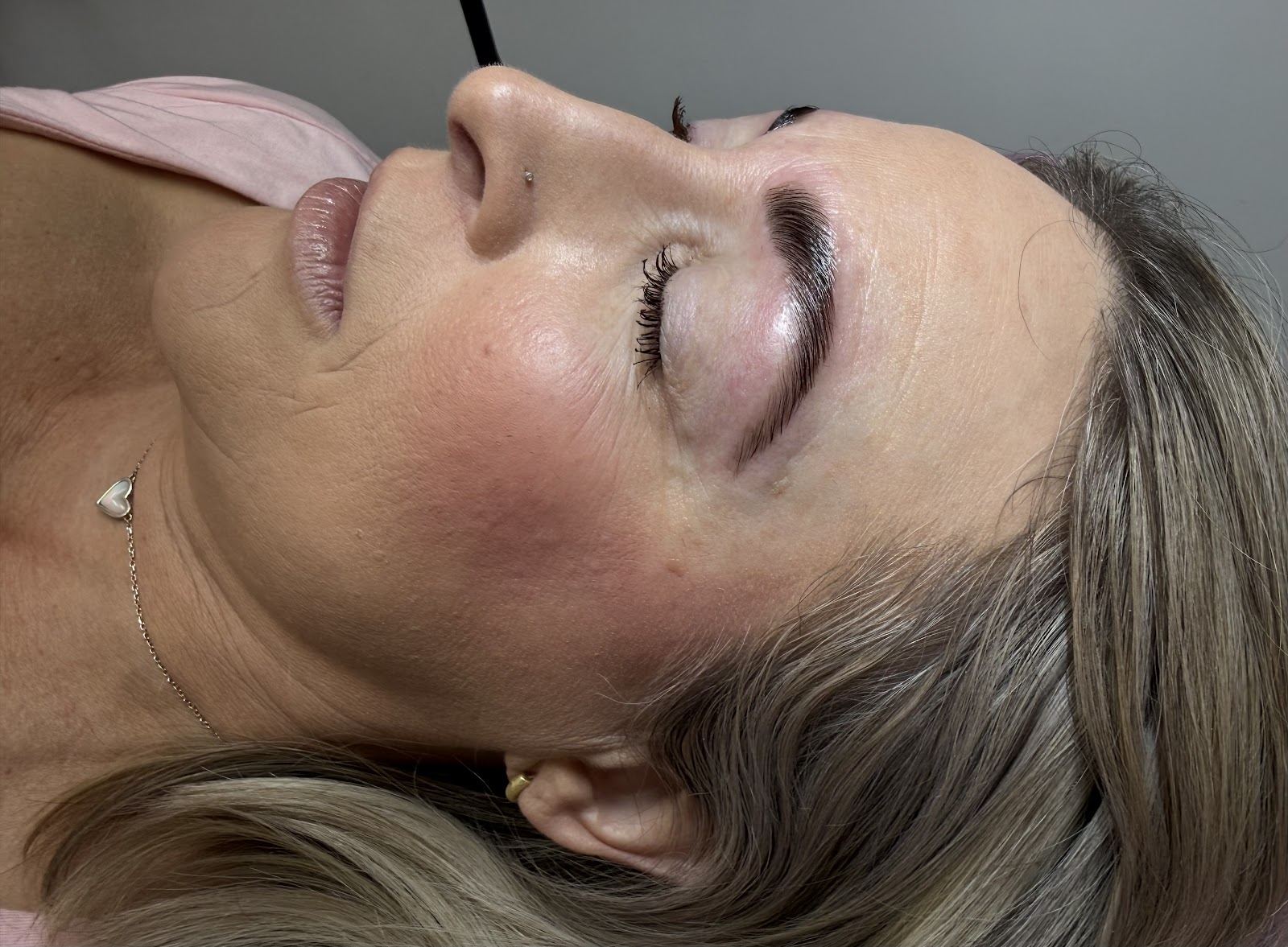 Client relaxing with freshly shaped, tinted brows and lifted lashes