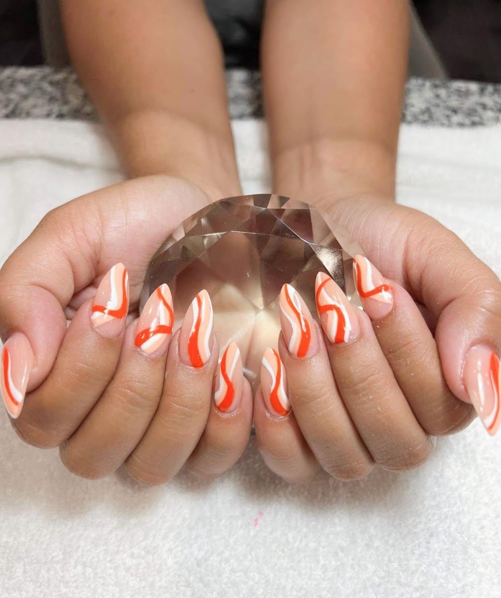 Orange and white swirl nails holding a crystal