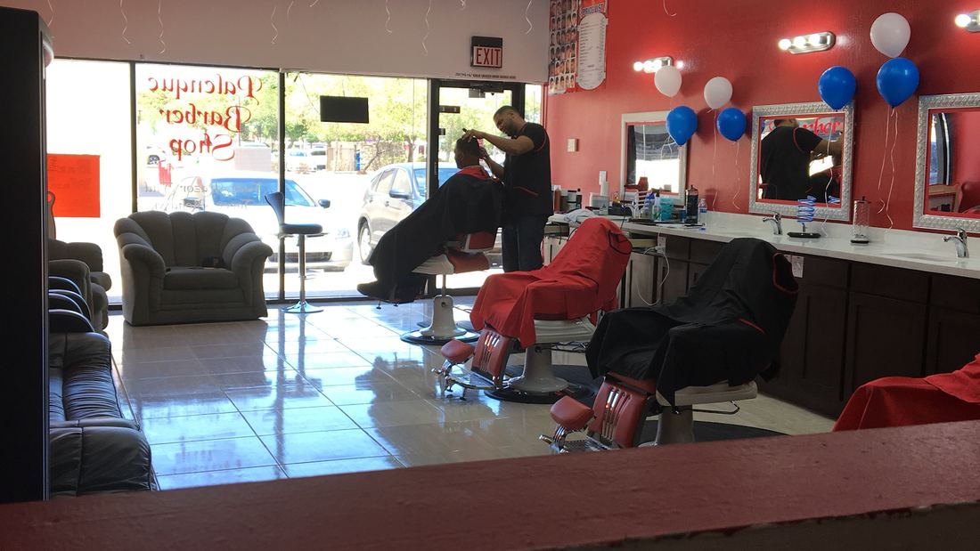 Barber at work in the shop, with chairs, mirrors and red walls