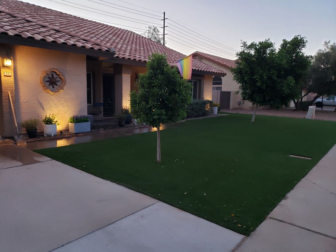 Front yard turf at dusk with a young tree and lit entry
