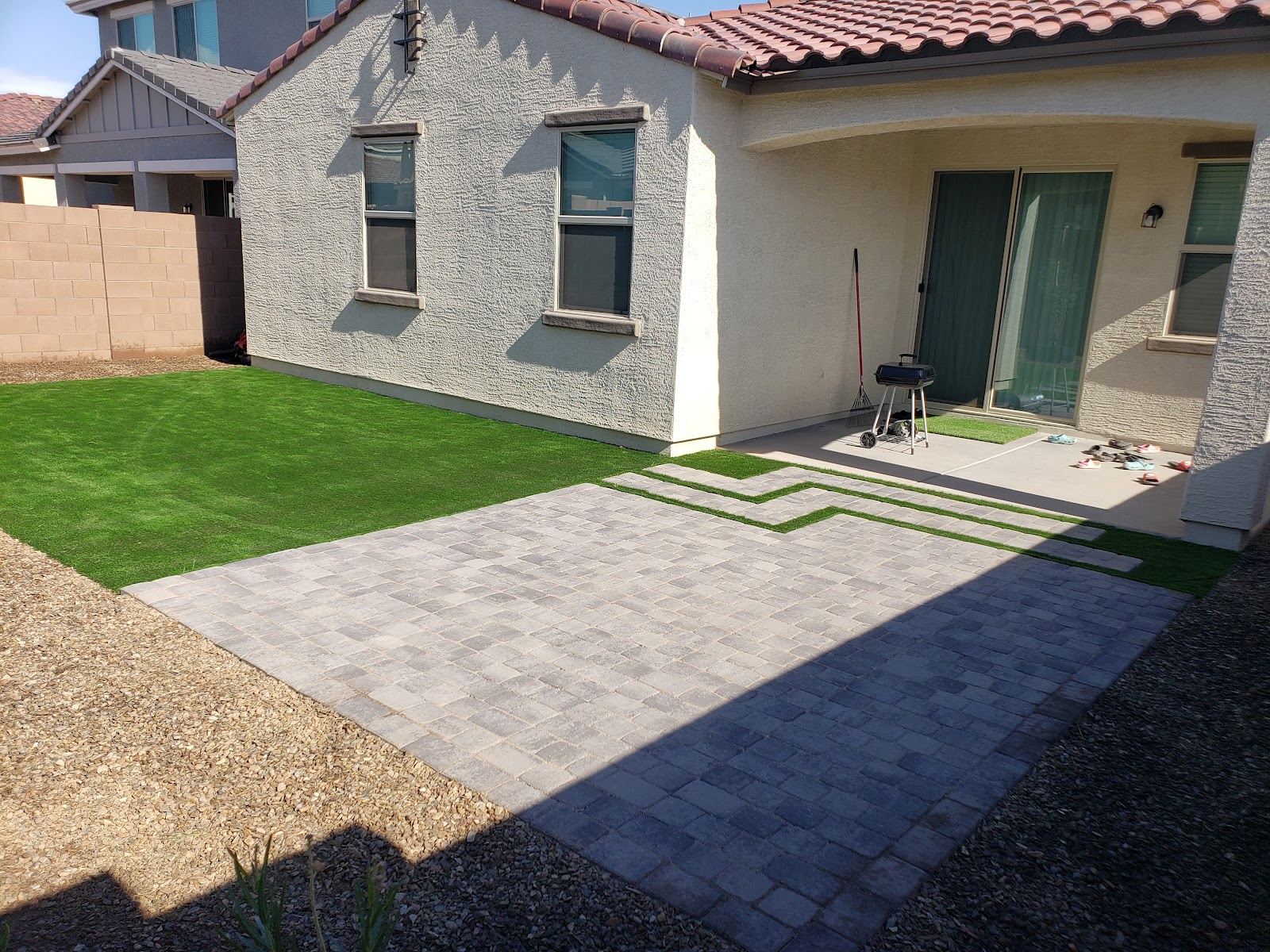 Front yard with green turf and a paver walkway leading to a stucco home