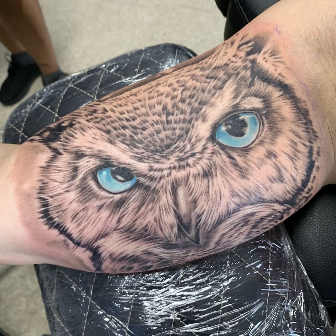 Realistic owl tattoo with bright blue eyes