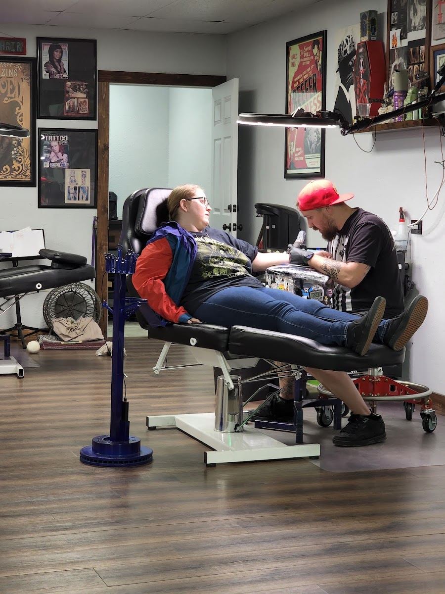 An artist tattooing a client in the ReINKarnate Tattoo shop in Mesa