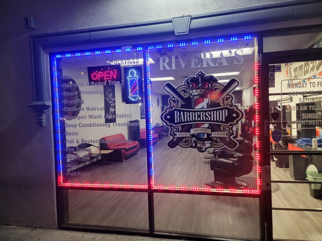 Rivera's Barbershop front window lit up at night with red and blue lights