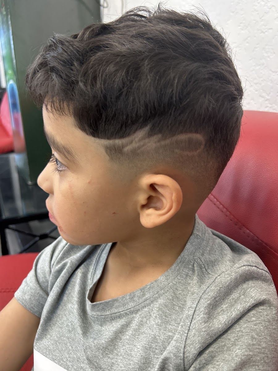 Young client with a fresh fade and a curved design cut into the side