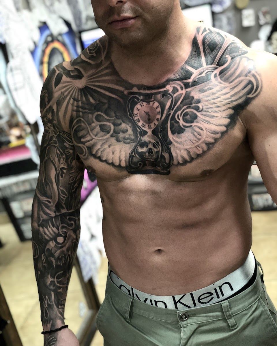 Full chest piece with wings and an hourglass, joined to a black and grey sleeve