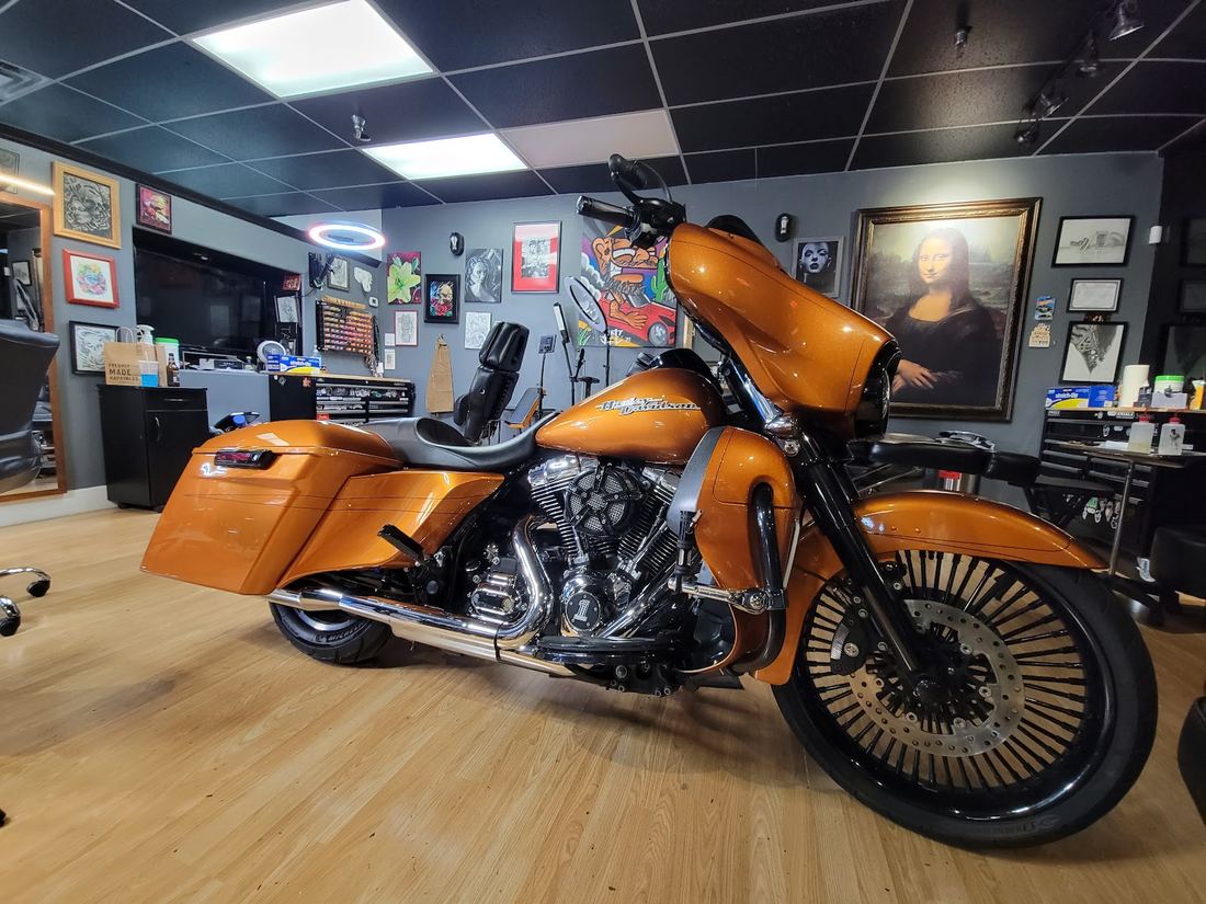 Inside Royal Craft Gallery: framed art on the walls and an orange motorcycle on the wood floor