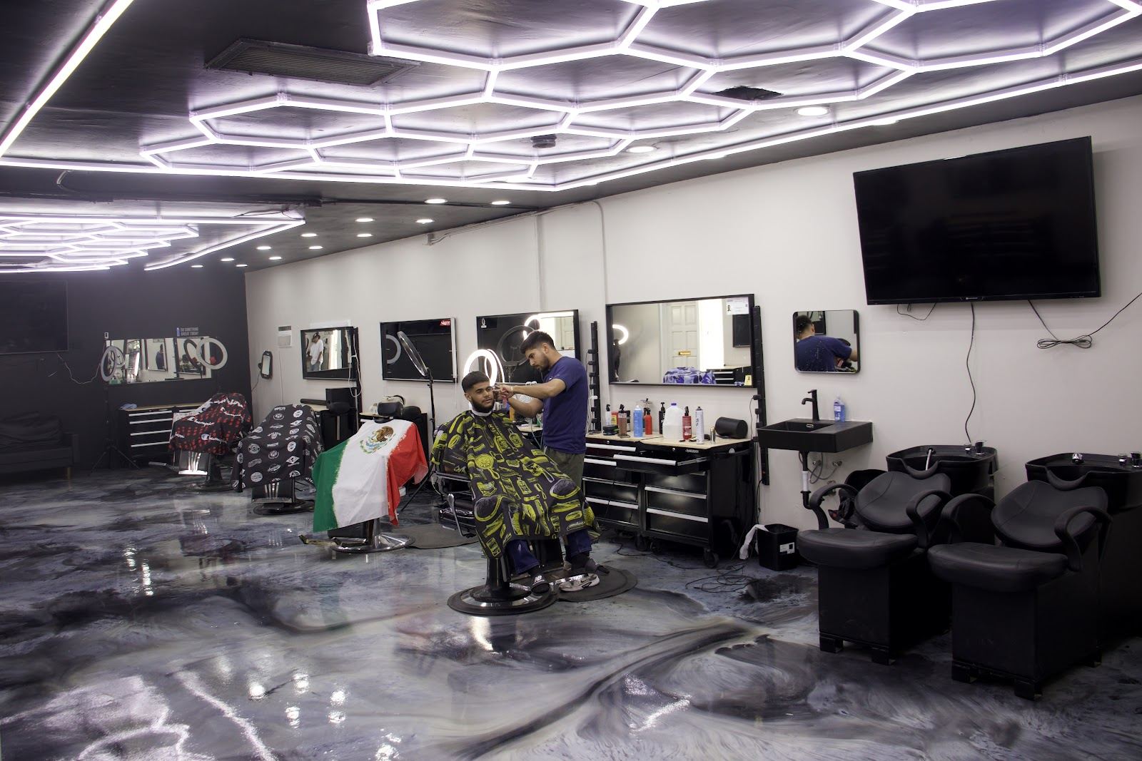 Inside Royal Fadez: hexagon light ceiling over a row of barber chairs and a marble floor