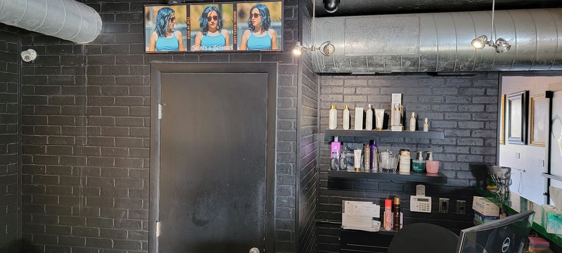 Black brick wall, silver ductwork and the front desk at Saints & Scissors