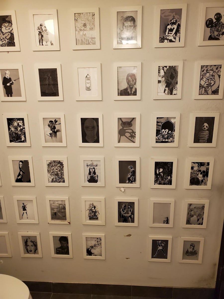 A wall of white-framed black and white prints inside the salon