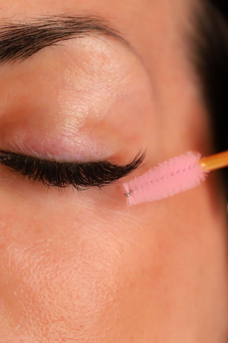 Lash extensions being brushed through with a pink spoolie