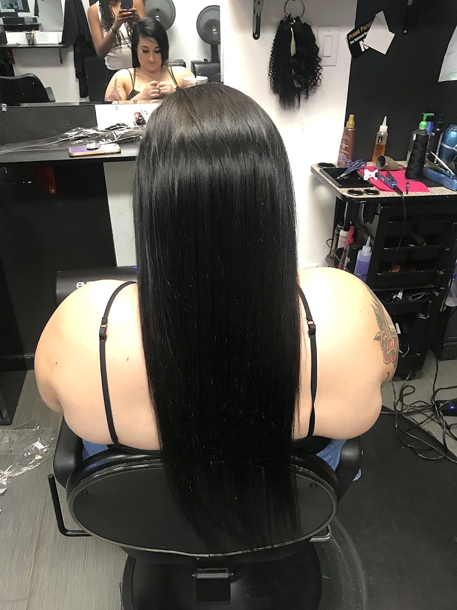 Back view of a client in the chair with long, glossy, bone-straight black hair