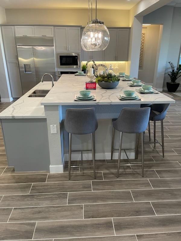 Kitchen island with white stone countertop, grey base and bar stools