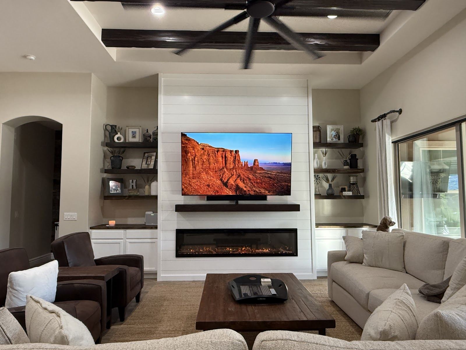 White shiplap fireplace wall with a mounted TV, linear electric fireplace and floating shelves on both sides