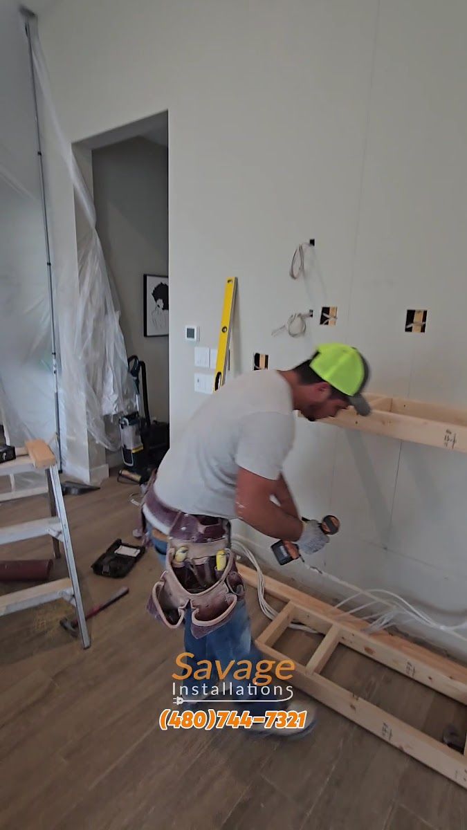 Savage Installations carpenter framing a wall build with a drill