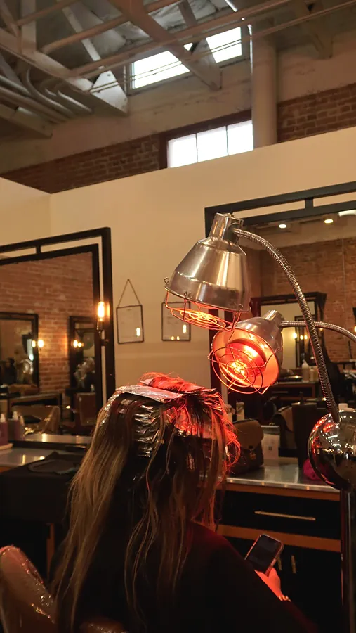 A heat lamp over a client's foils at a station against the red brick wall