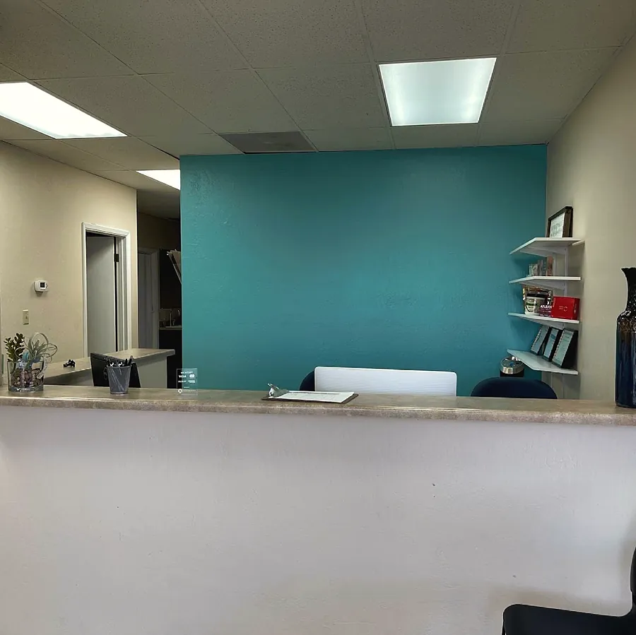 The front desk: a white counter in front of a teal accent wall with white shelves