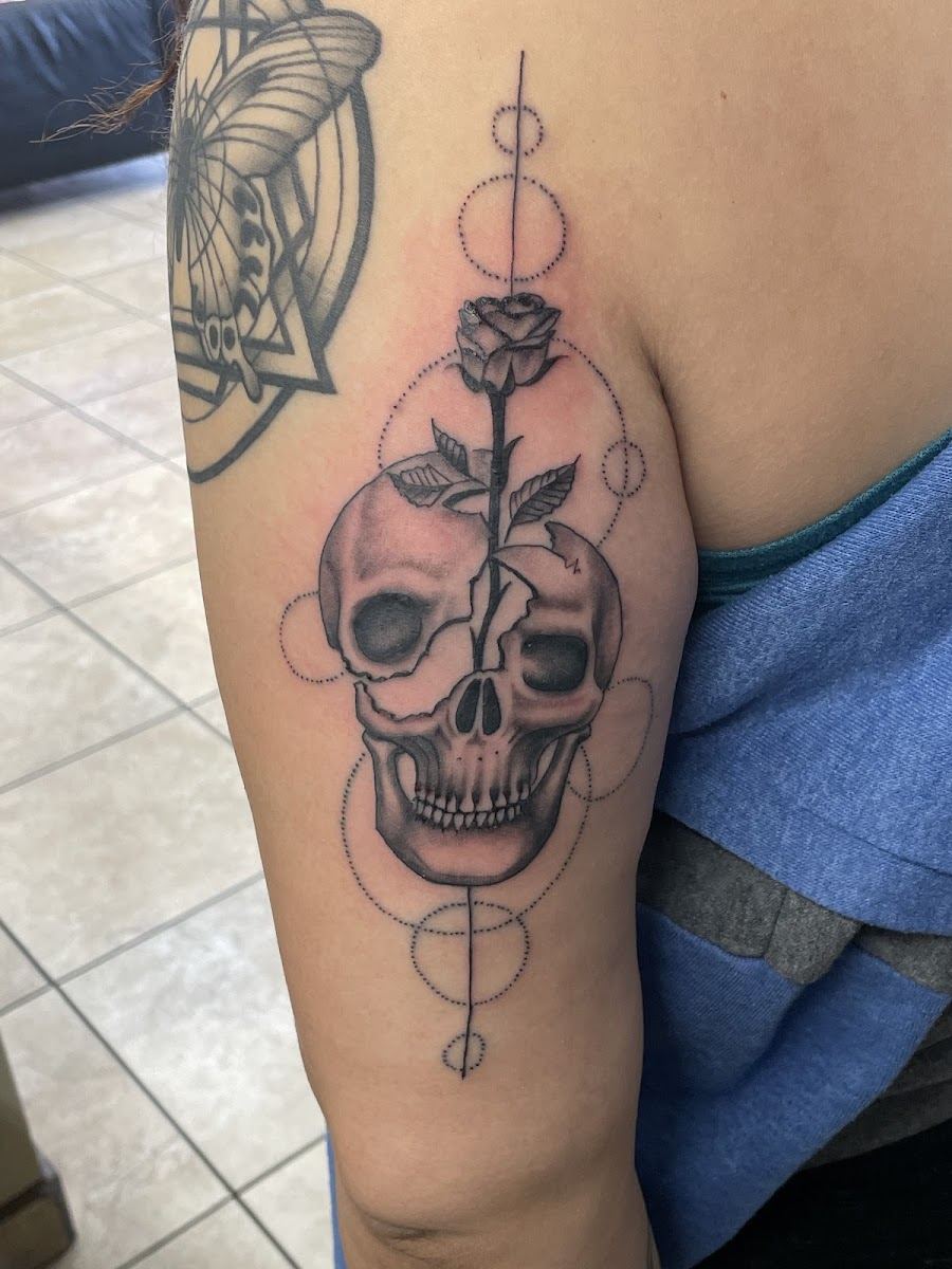 Fine line skull and rose tattoo on an upper arm
