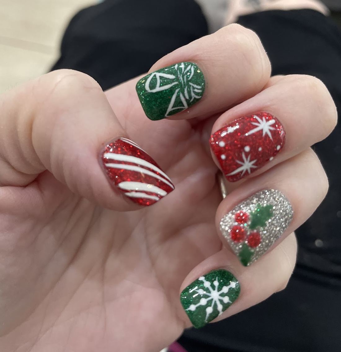 Holiday nail art in red and green with candy cane stripes, snowflakes and silver glitter