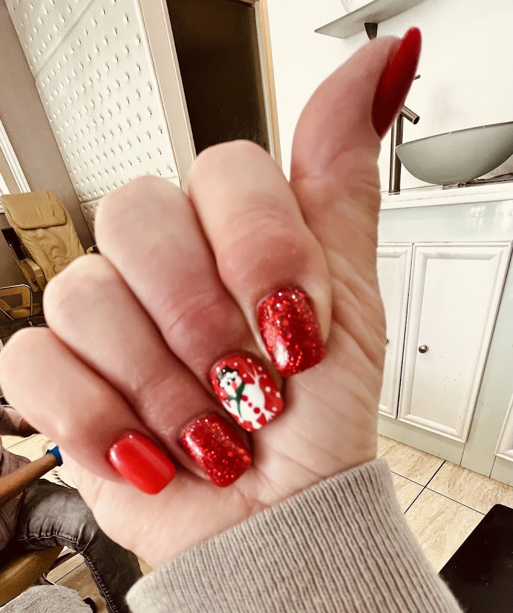 A hand with glossy red and red glitter nails, one accent nail painted with a snowman