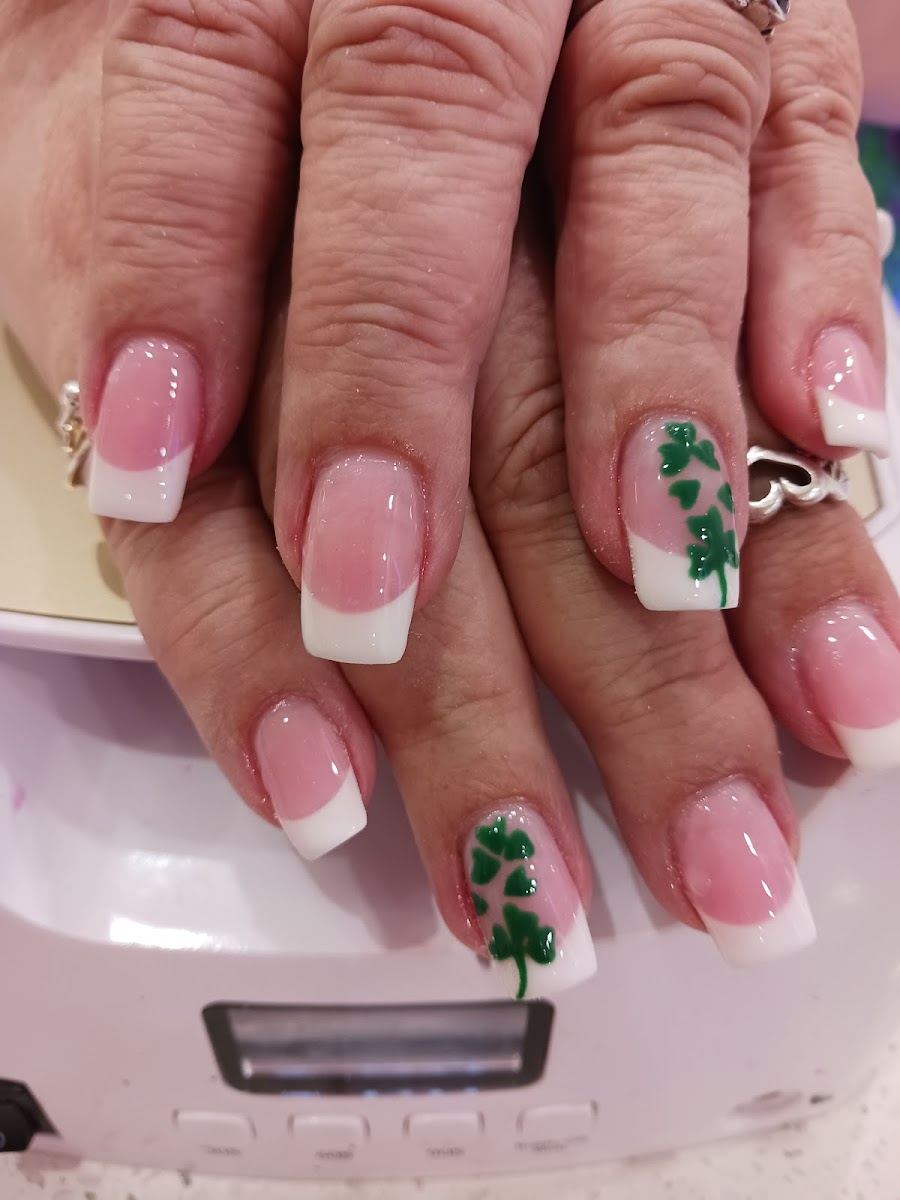 Pink and white French nails with hand-painted green shamrock accents