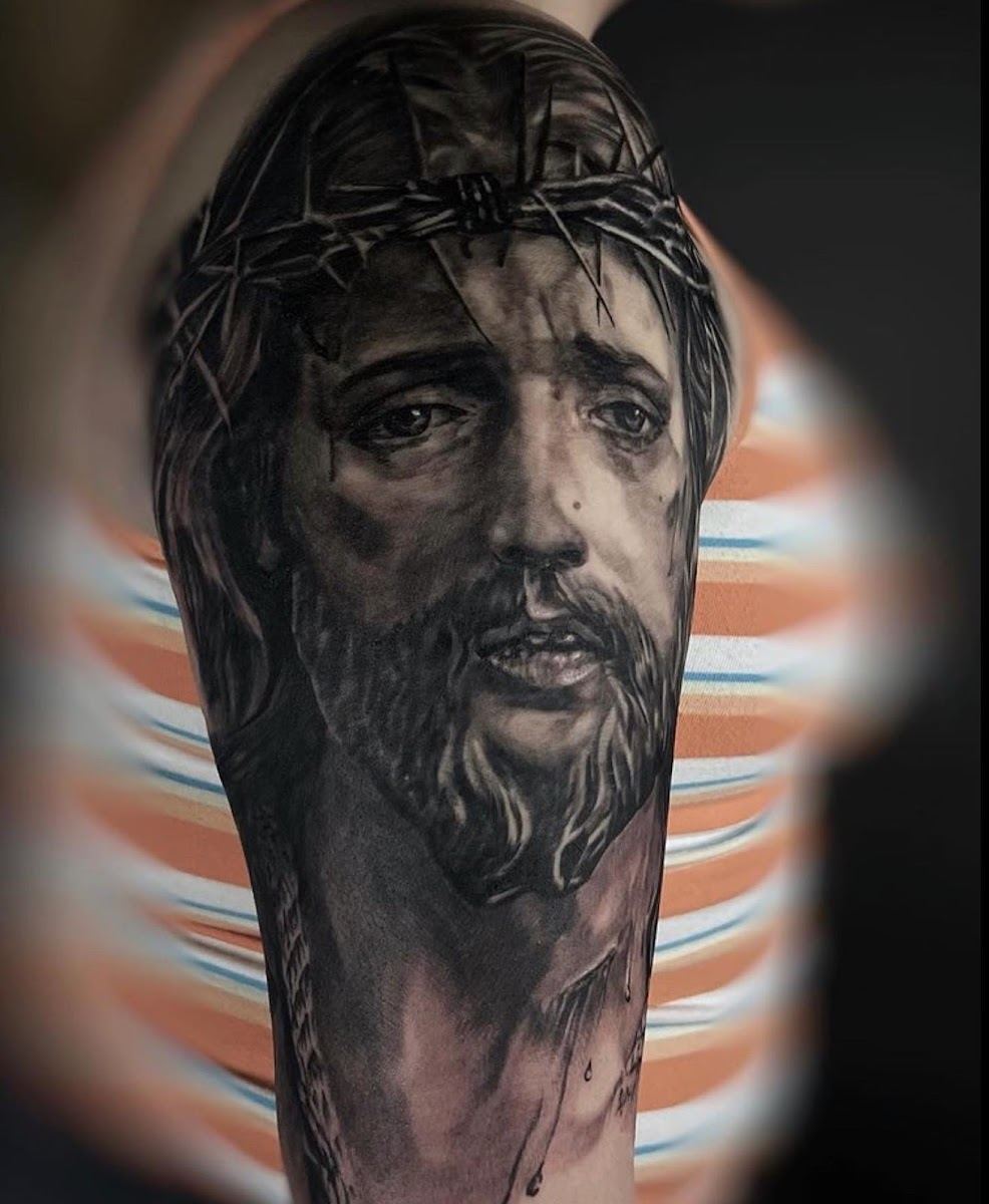 Black and grey realism tattoo of a portrait of Christ with a crown of thorns on a forearm
