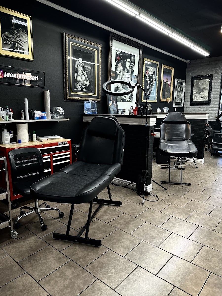 Tattoo stations with black chairs and framed artwork inside the studio