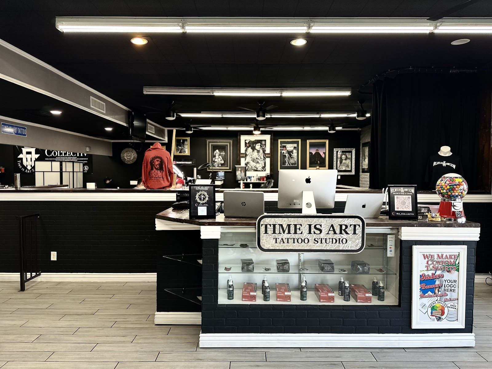 Inside Time is Art Tattoo Studios: the front counter with the shop sign and framed art on black walls