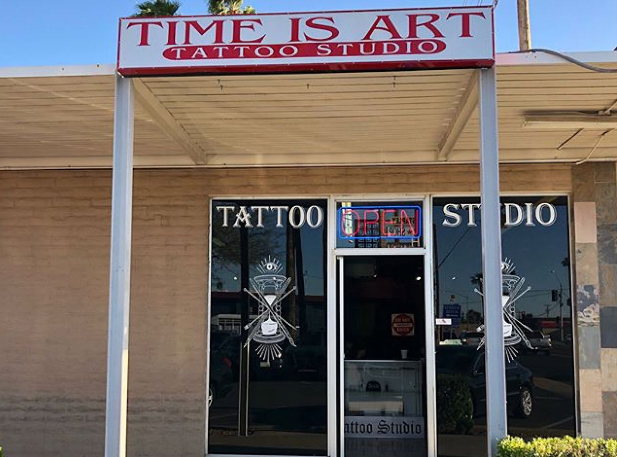 Storefront of Time is Art Tattoo Studio with the red and white sign and an Open sign in the window