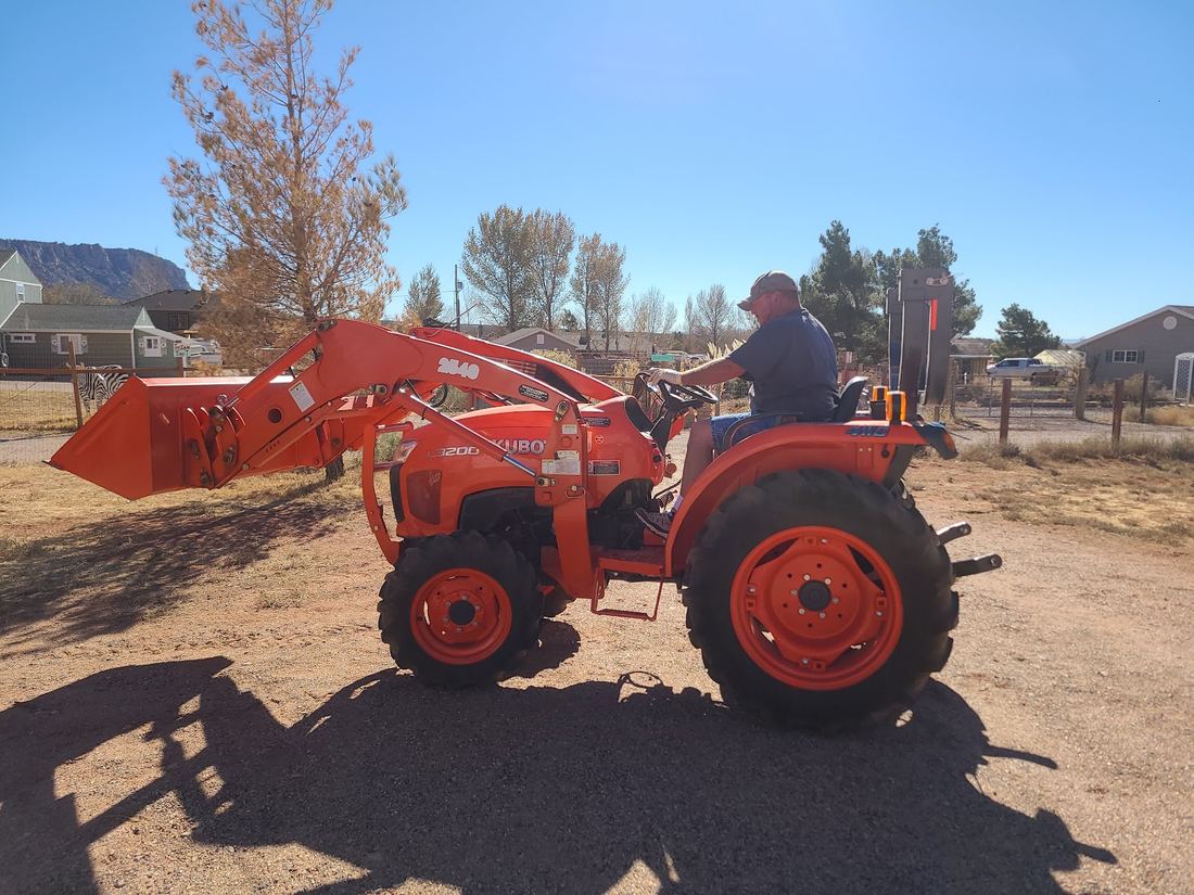 Orange compact tractor with front loader on a dirt lot