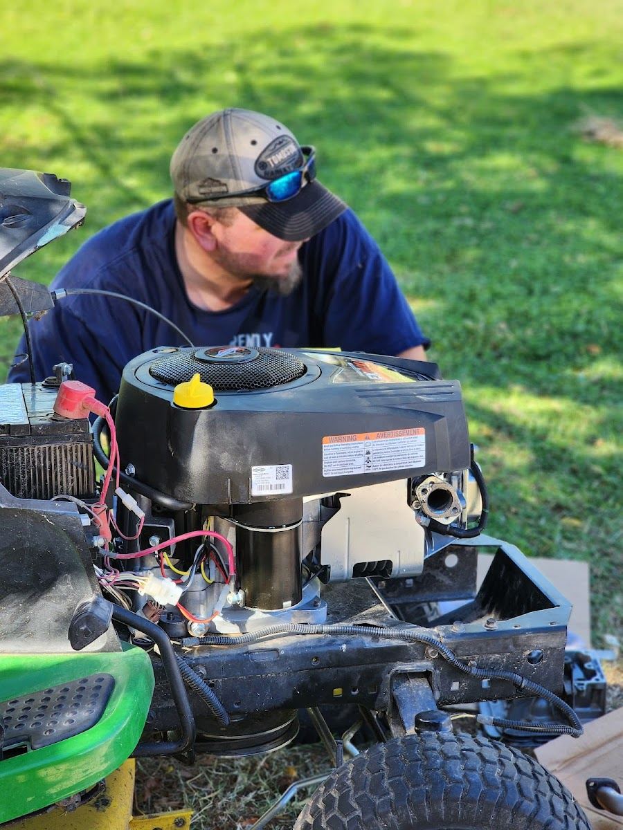 Tinx technician working on a riding mower engine outdoors