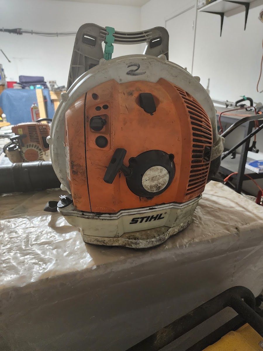 Orange backpack blower engine on a workbench