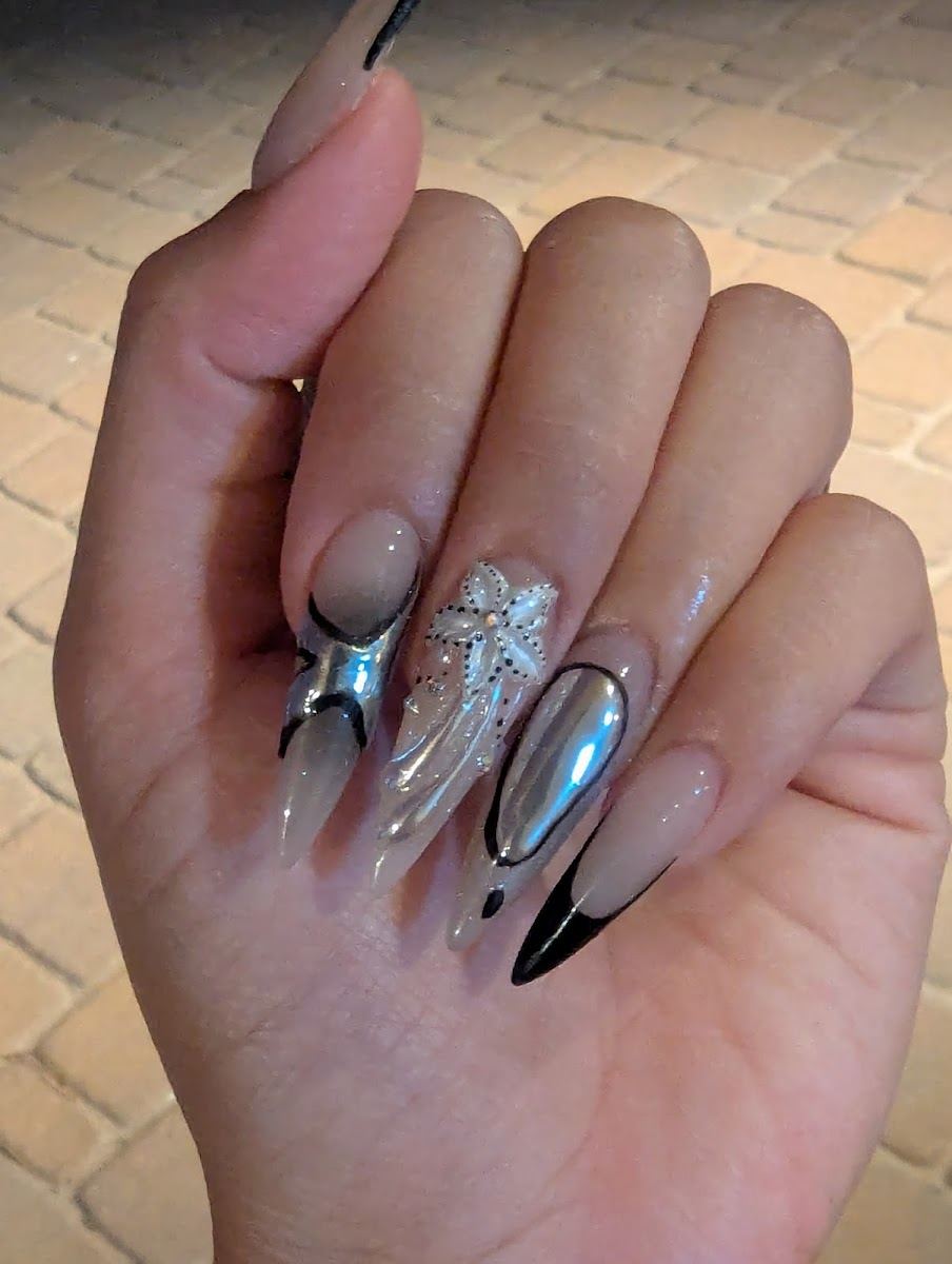 Nude almond nails with chrome swirls, rhinestones and black tips
