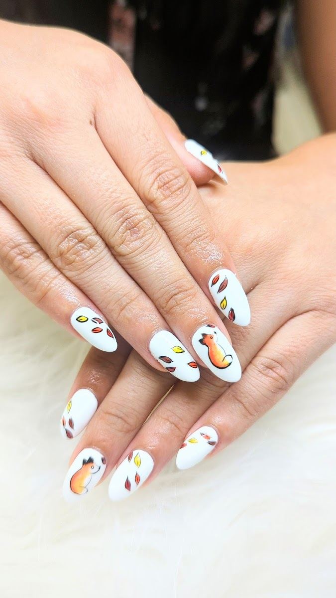 White almond nails painted with autumn leaves