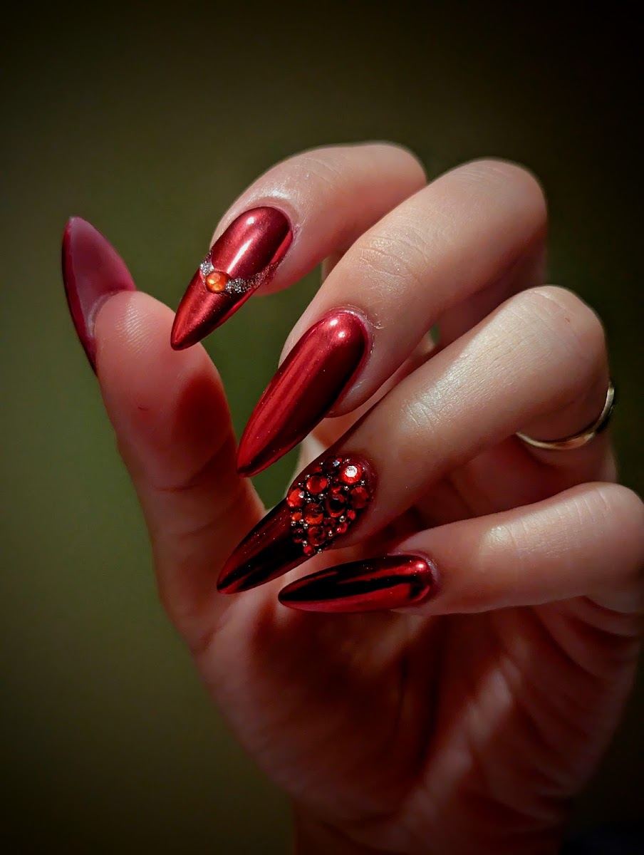 Long red chrome stiletto nails with a red rhinestone accent nail