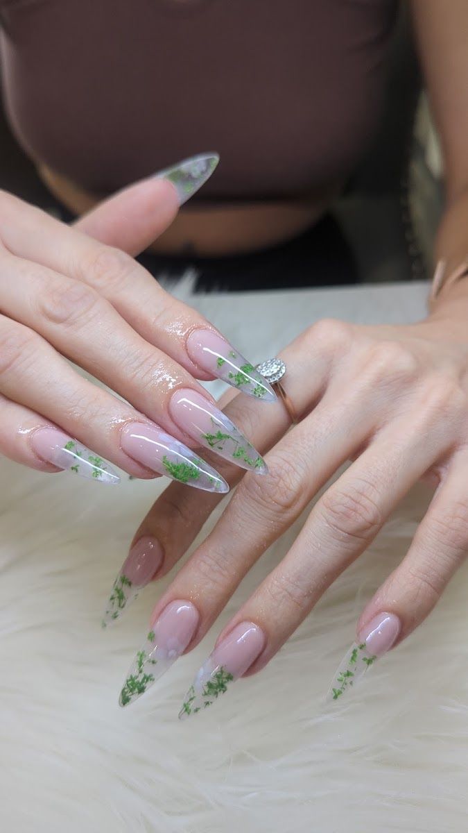 Long clear stiletto nails with green leaf art at the tips