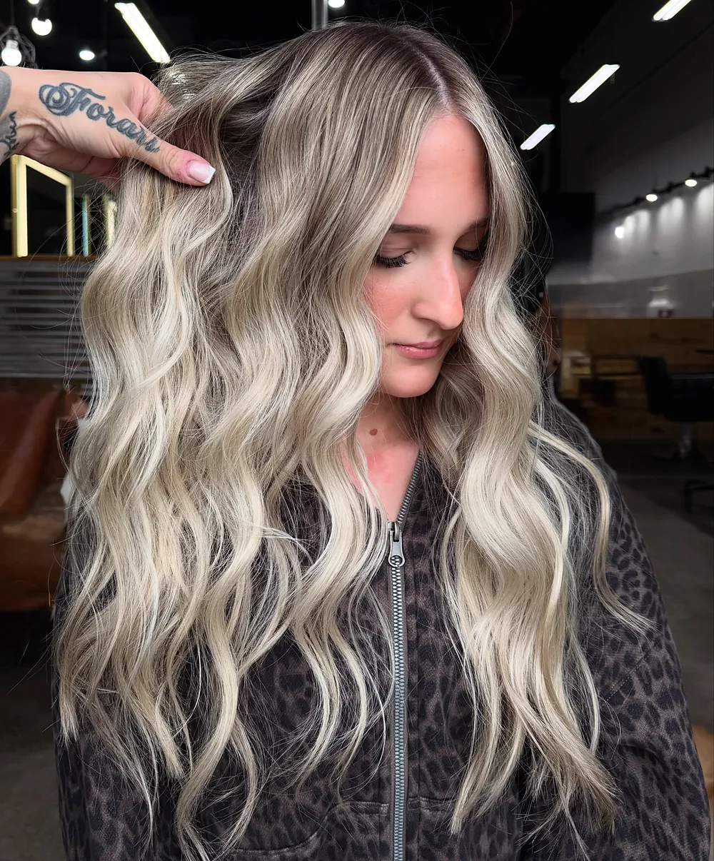 Long blended blonde waves with a darker root, held up to the light