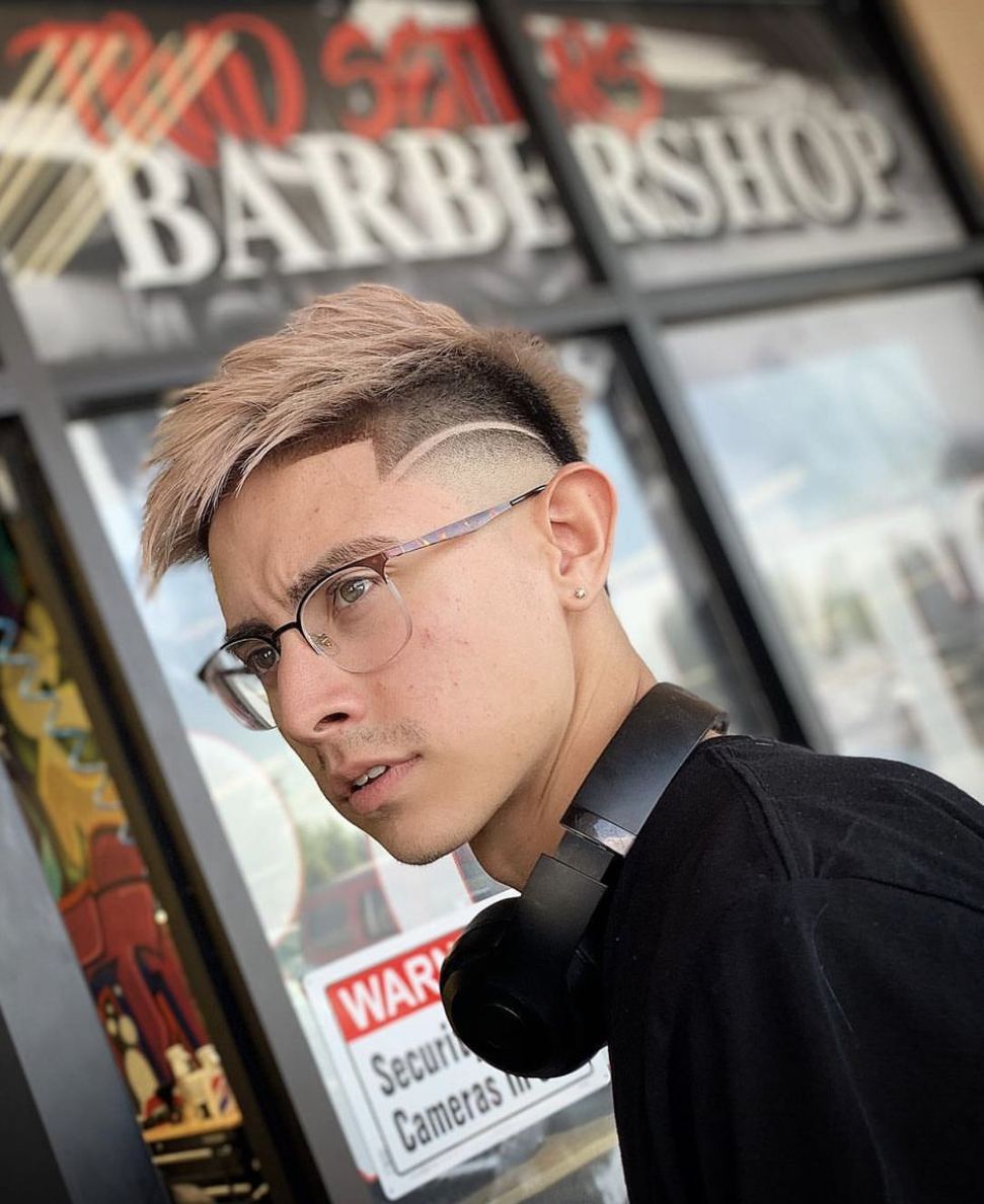 Client with blonde textured hair, a skin fade and a shaved part outside the barbershop window
