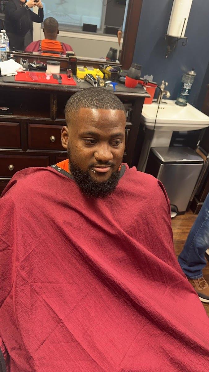 Client with a fresh short cut and full beard under a red cape