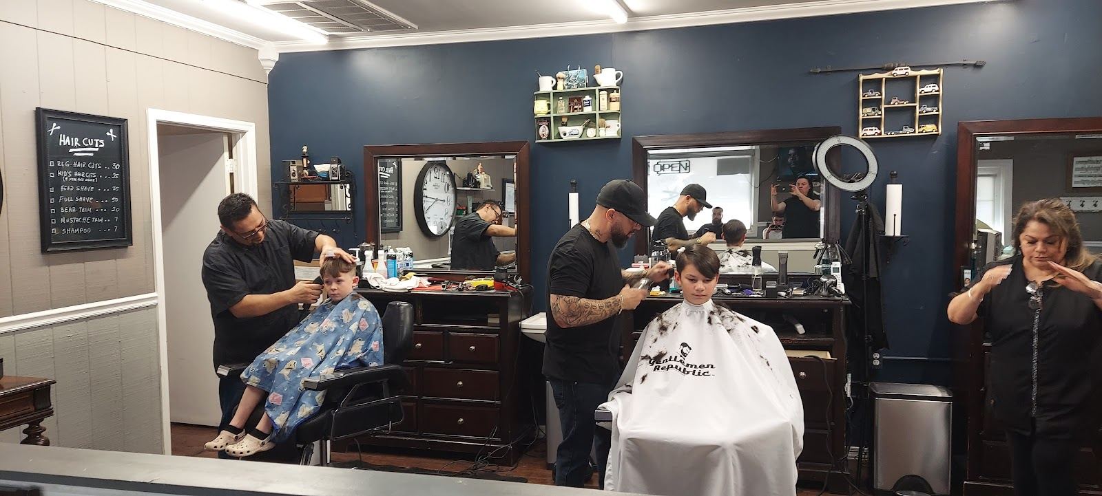 Barbers cutting two boys' hair side by side at Two Guys Barber Shop