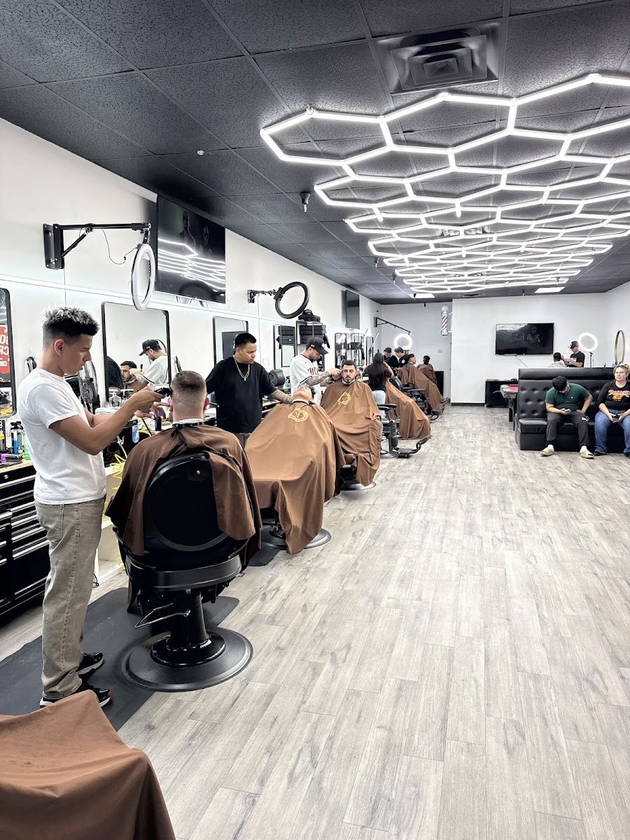 Barbers working a full row of chairs under hexagon ceiling lights