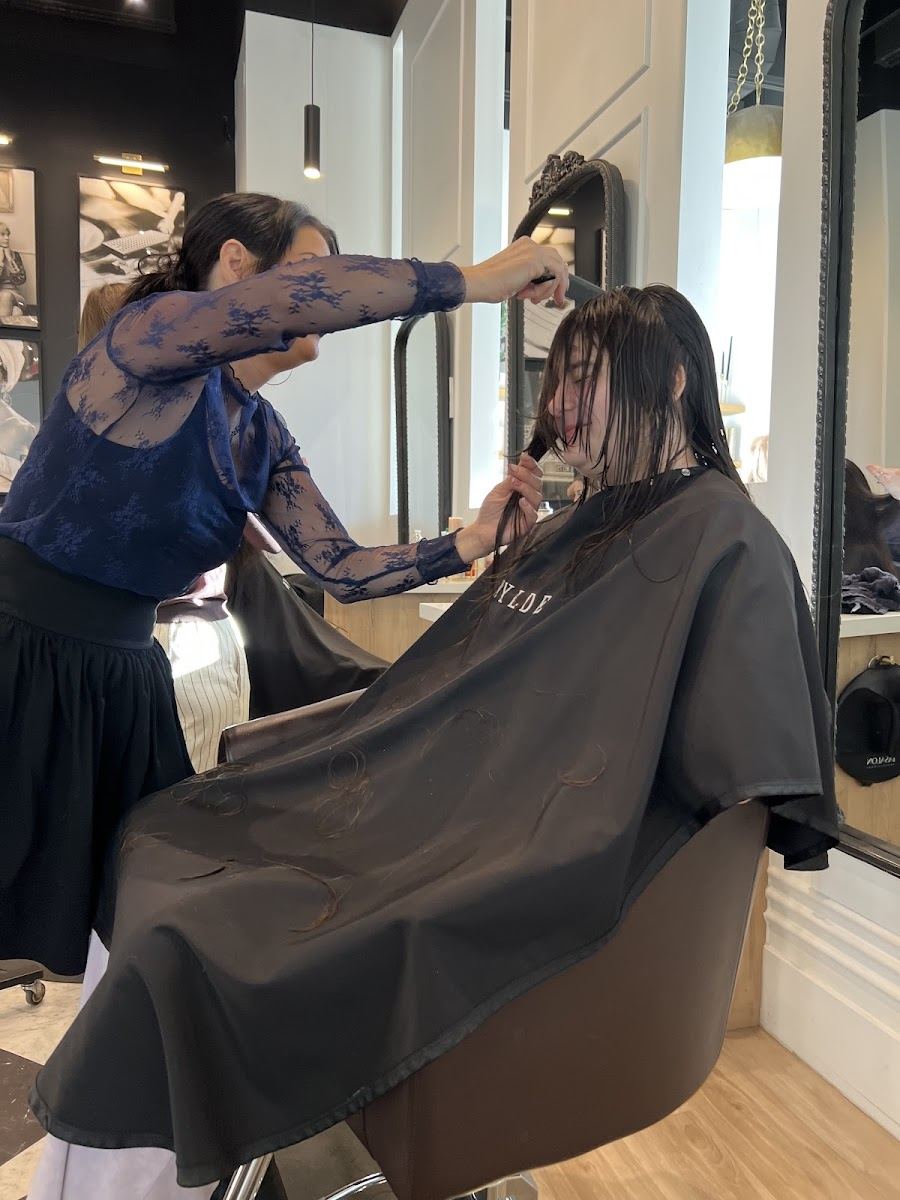 A stylist cutting a client's hair at the mirror